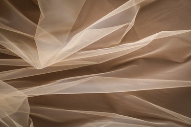 Beautiful tulle fabric on brown background, top view