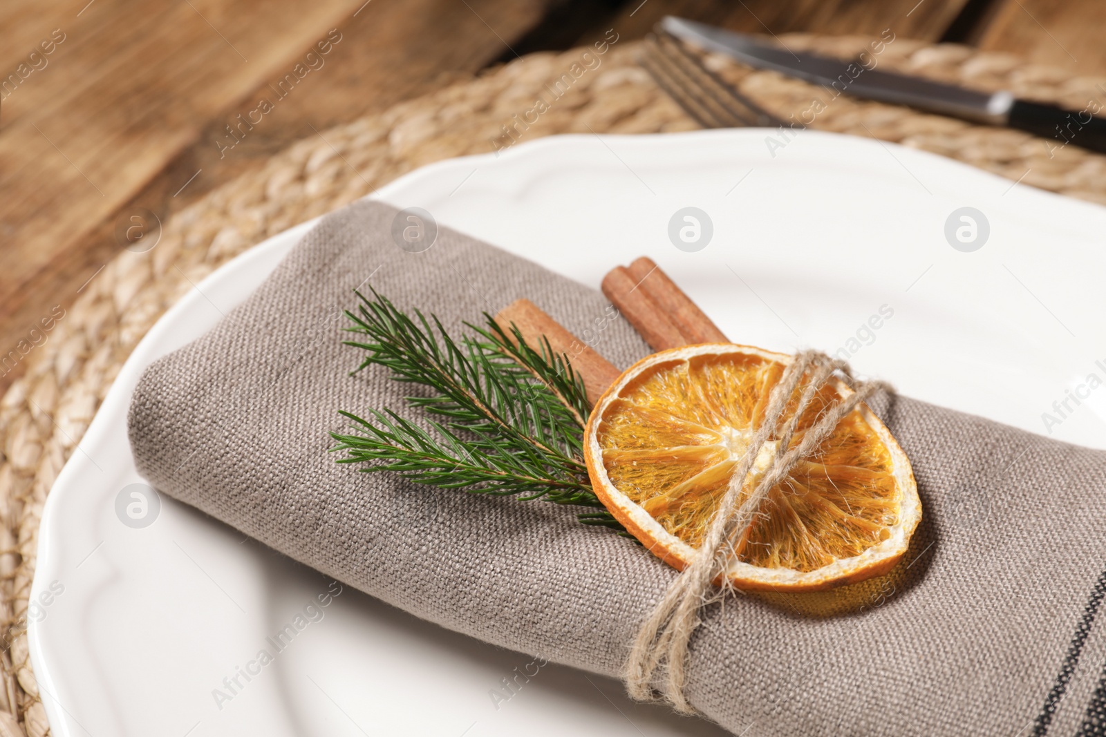 Photo of Beautiful dishware, fabric napkin and dried orange slice, closeup. Christmas table setting