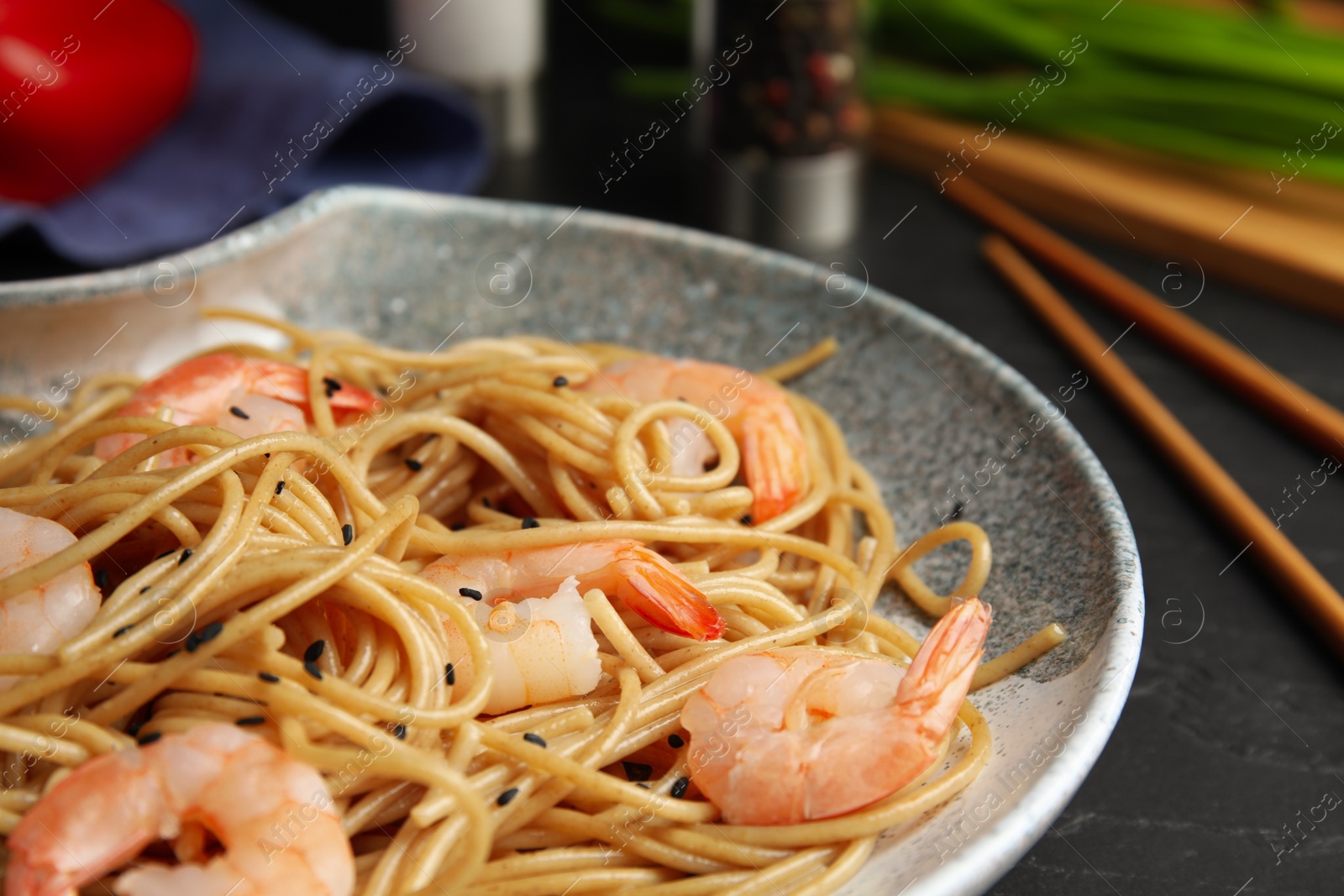 Photo of Tasty buckwheat noodles with shrimps on black table, closeup