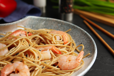 Photo of Tasty buckwheat noodles with shrimps on black table, closeup