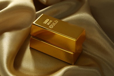 Photo of Gold bars on shiny silk fabric, closeup
