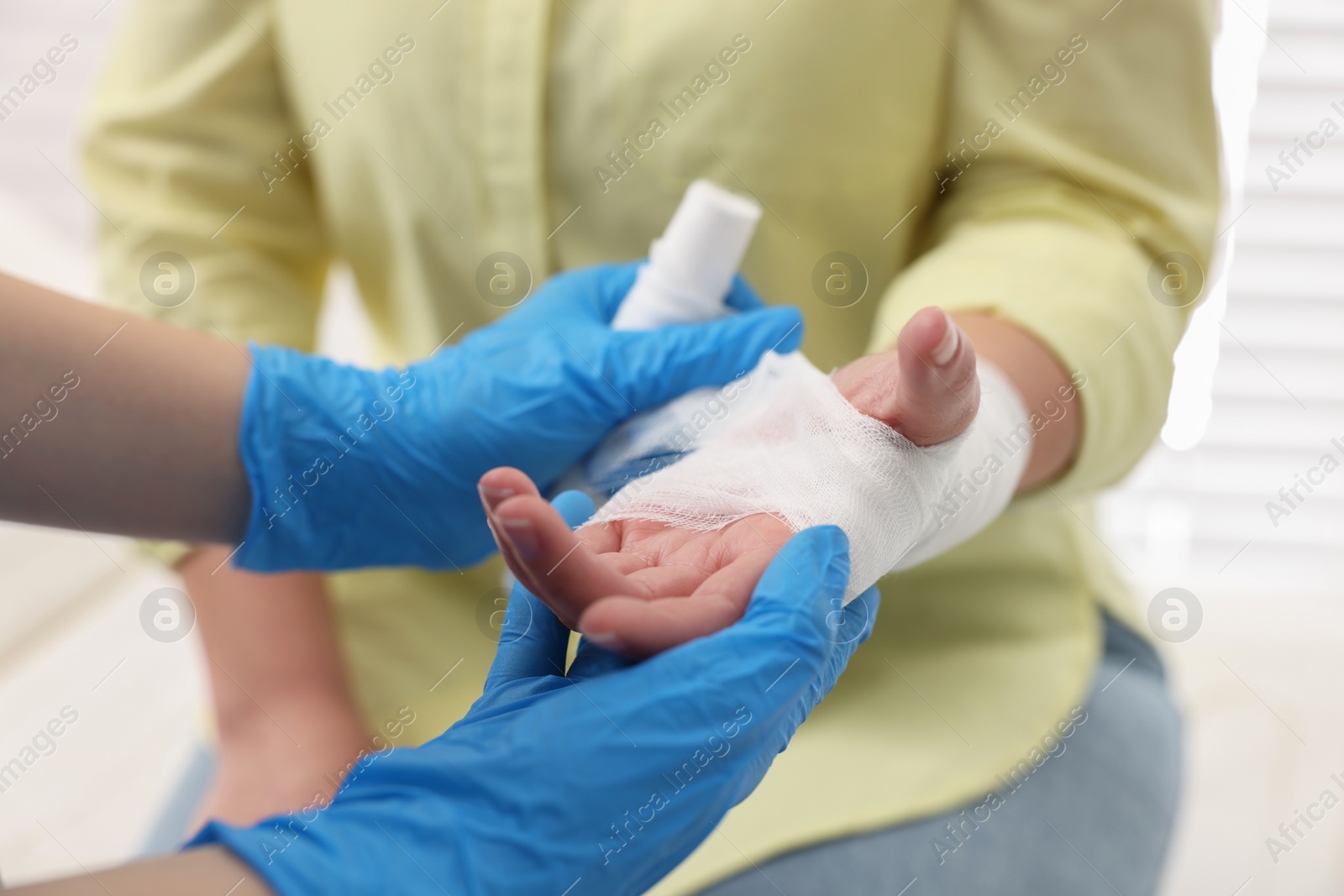 Photo of Doctor bandaging patient's burned hand indoors, closeup