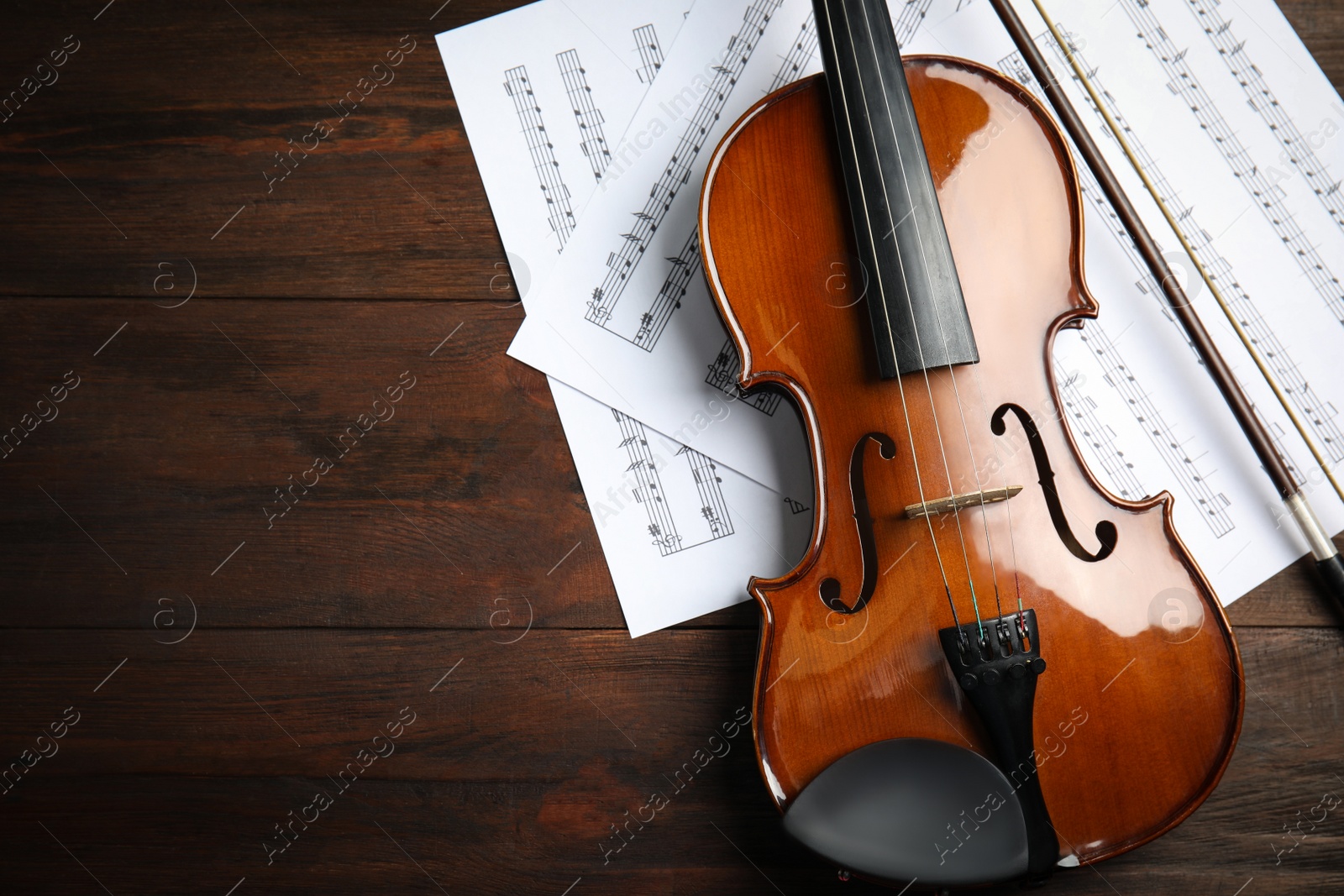 Photo of Beautiful violin, bow and note sheets on wooden table, flat lay. Space for text