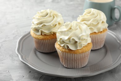 Photo of Tasty cupcakes with vanilla cream on grey table, closeup