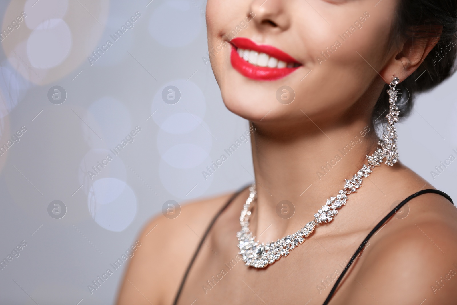 Photo of Beautiful woman with elegant jewelry on blurred background, closeup. Space for text