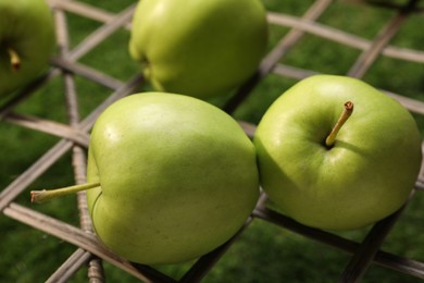 Photo of Fresh green apples on rattan grid, closeup