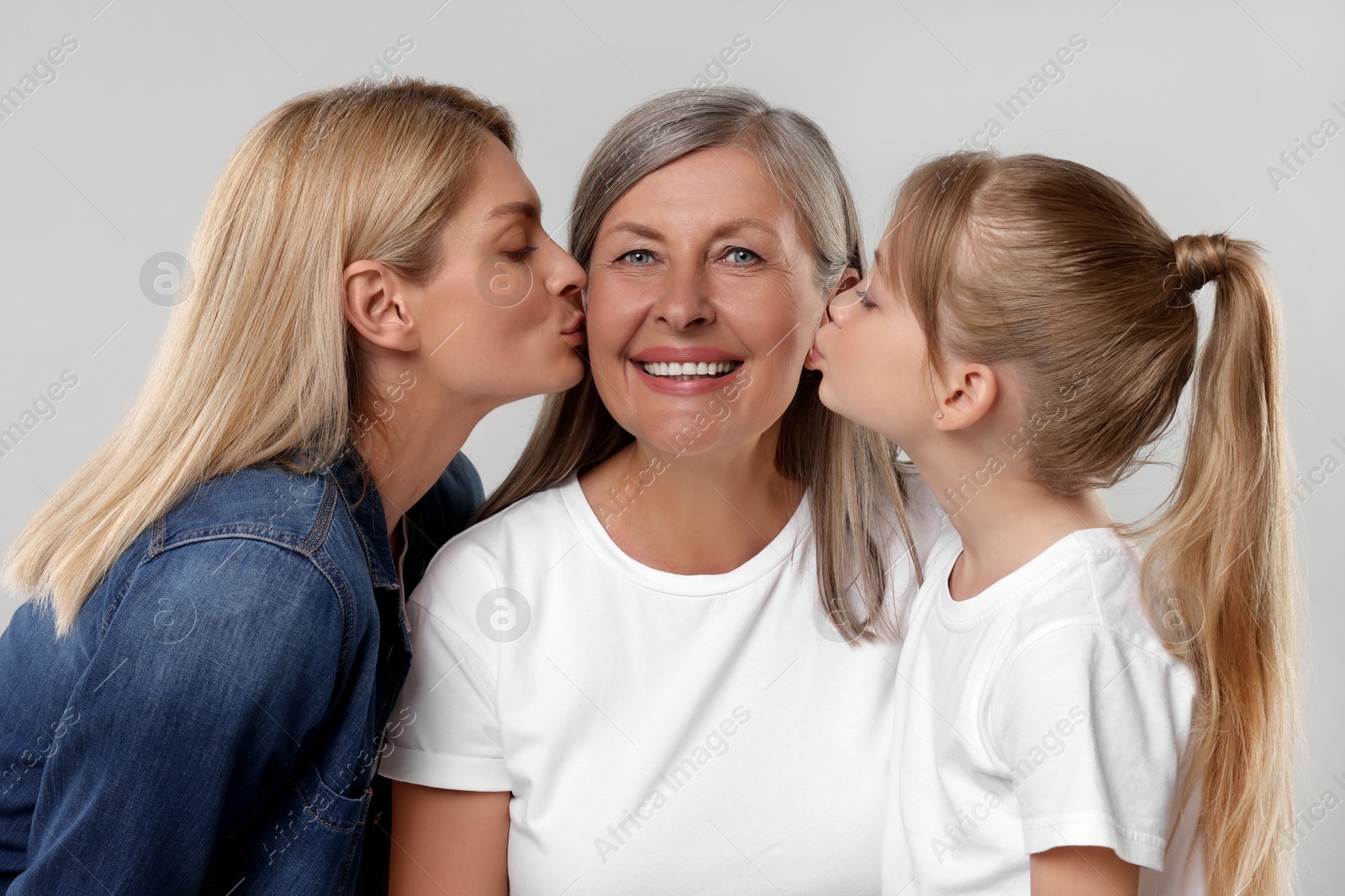 Photo of Three generations. Happy grandmother, her daughter and granddaughter on light gray background