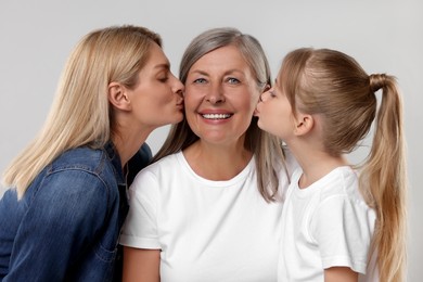 Photo of Three generations. Happy grandmother, her daughter and granddaughter on light gray background