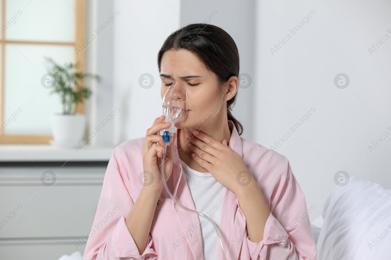 Photo of Sick young woman using nebulizer at home