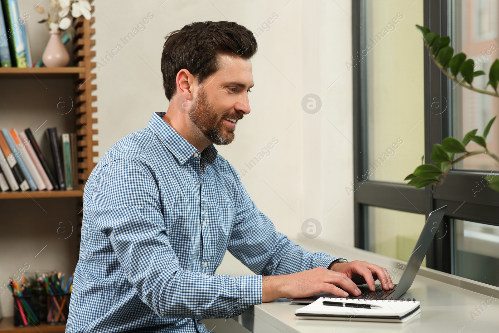 Photo of Man working on laptop at table in cafe