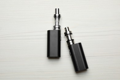 Photo of Electronic cigarettes on white wooden table, flat lay. Smoking alternative