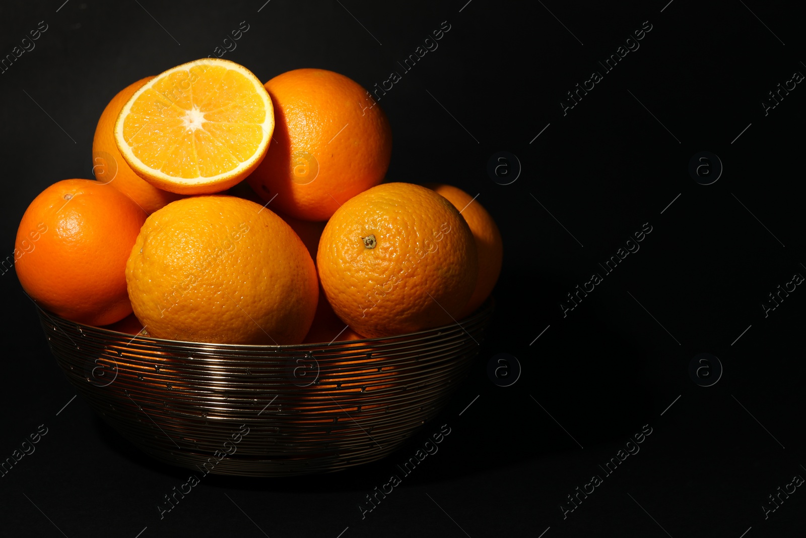 Photo of Bowl with ripe juicy oranges on black background. Space for text