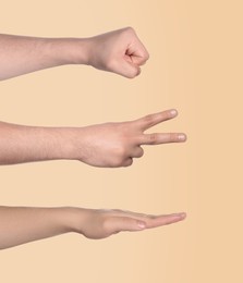 People playing rock, paper and scissors on beige background, closeup