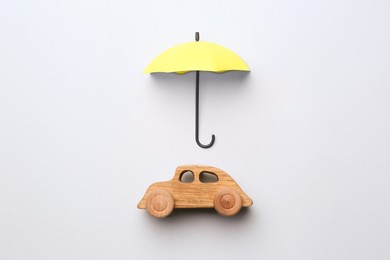Photo of Mini umbrella and toy car on white background, top view