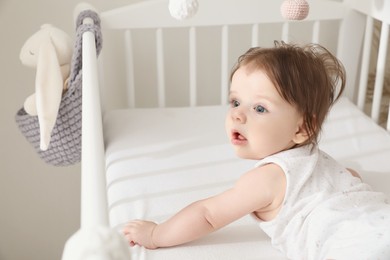 Cute little baby lying in comfortable crib at home, space for text