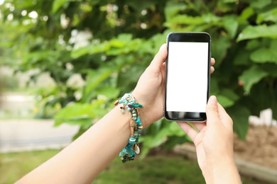 Photo of Woman holding smartphone with blank screen outdoors. Mockup for design