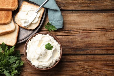 Photo of Toasted bread and delicious cream cheese with parsley on wooden table, flat lay. Space for text