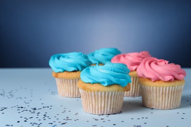 Photo of Delicious cupcakes with bright cream and confetti on blue background, space for text