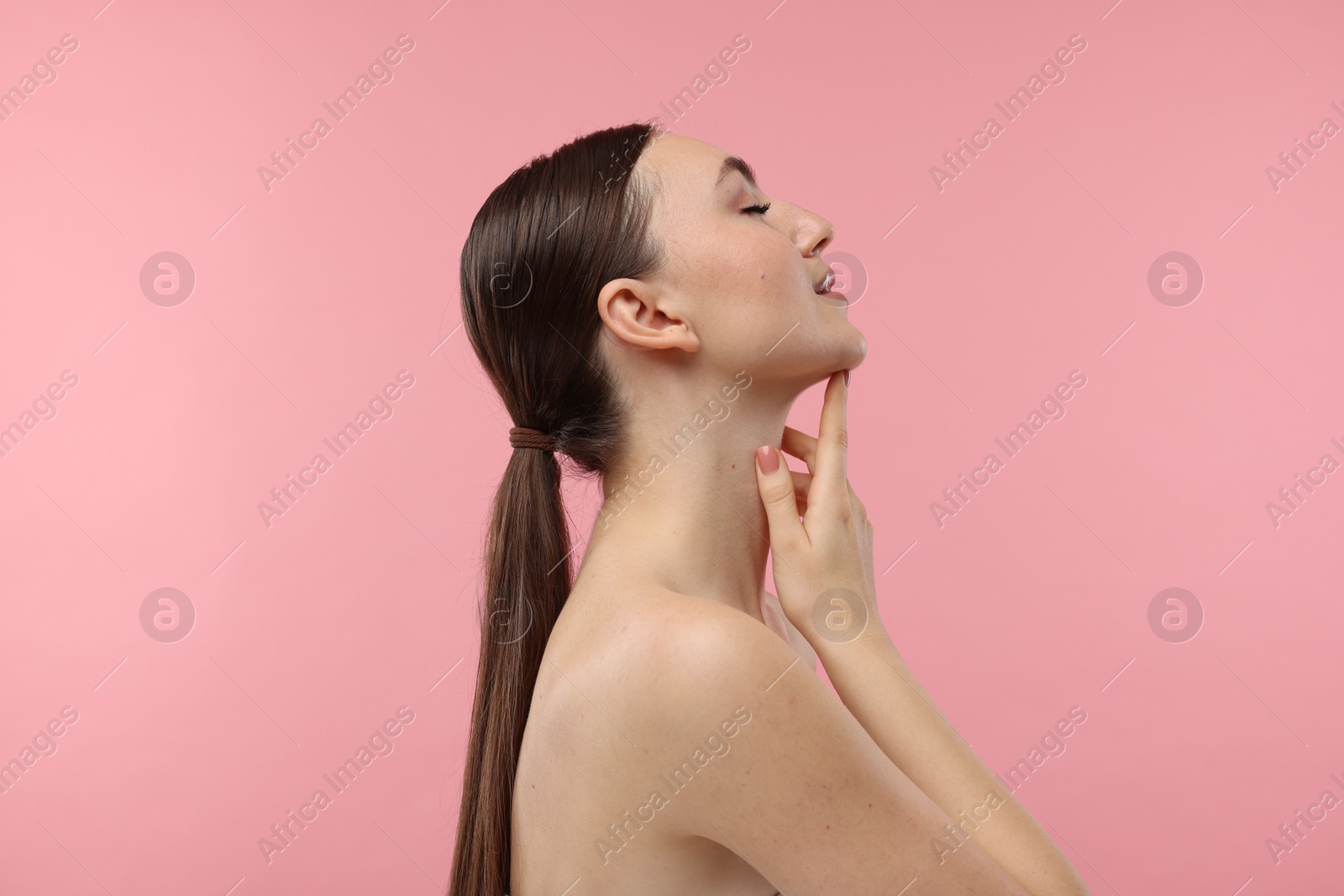 Photo of Beautiful woman touching her chin on pink background