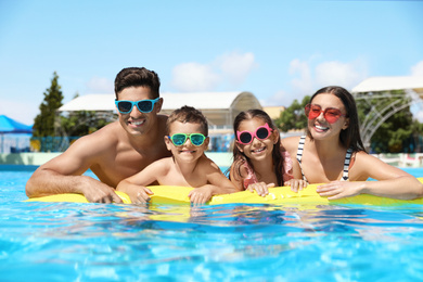 Happy family with inflatable mattress in swimming pool. Summer vacation