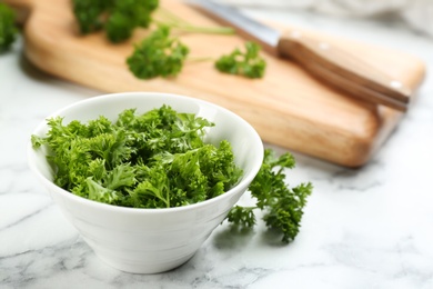 Cut curly parsley in bowl on white marble table