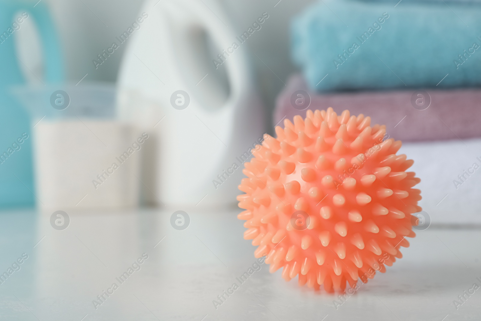 Photo of Orange dryer ball on white table, closeup. Space for text