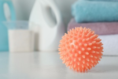 Orange dryer ball on white table, closeup. Space for text