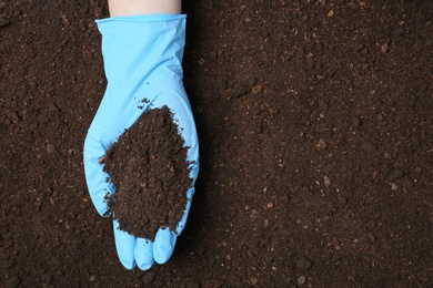Photo of Scientist holding pile of soil above ground, top view. Space for text