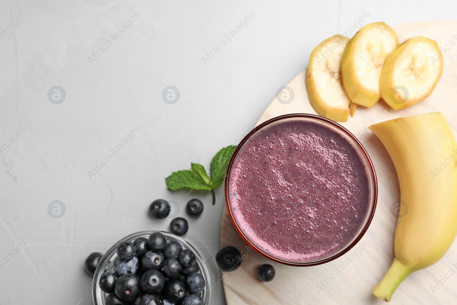 Photo of Fresh acai drink with berries and banana on grey background, flat lay. Space for text