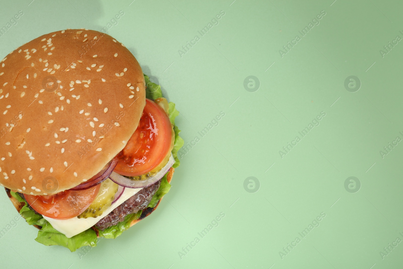 Photo of Burger with delicious patty on green background, top view. Space for text