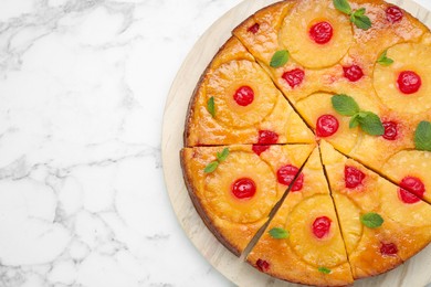 Photo of Delicious cut pineapple pie with cherry and mint on white marble table, top view. Space for text