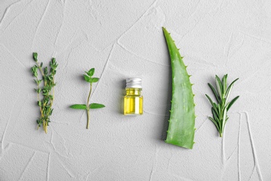 Photo of Bottle with essential oils and fresh herbs on light background, flat lay