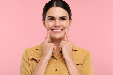 Photo of Woman showing her clean teeth and smiling on pink background