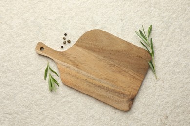 Photo of Cutting board, pepper and rosemary on white textured table, flat lay. Space for text