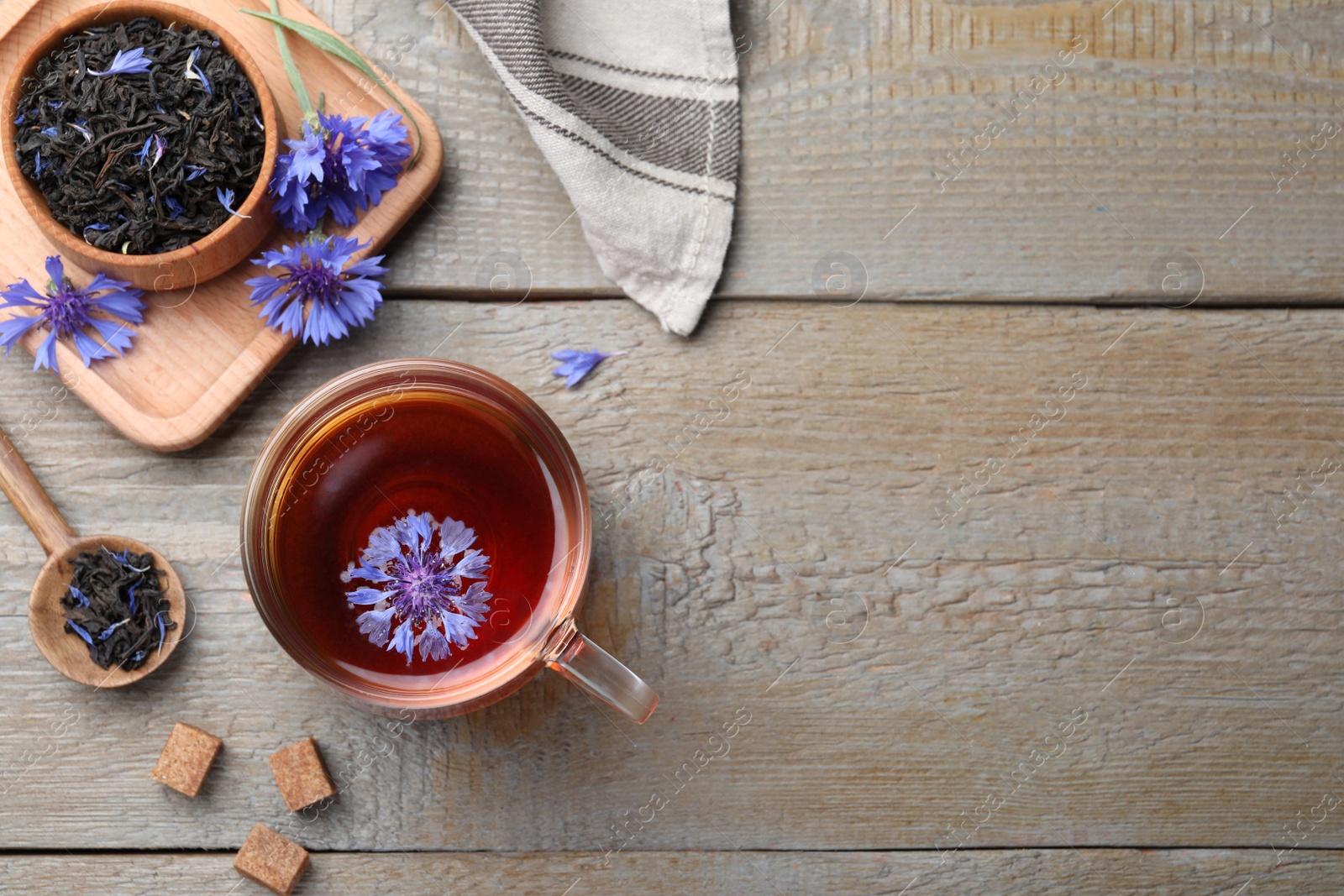 Photo of Flat lay composition with tea and cornflowers on wooden table. Space for text