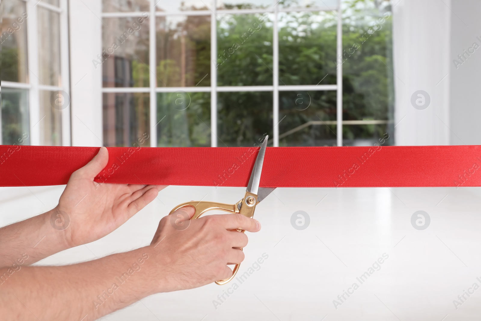 Photo of Man cutting red ribbon on blurred background. Festive ceremony