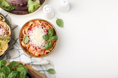 Delicious pasta with tomato sauce, basil and parmesan cheese on white table, flat lay. Space for text