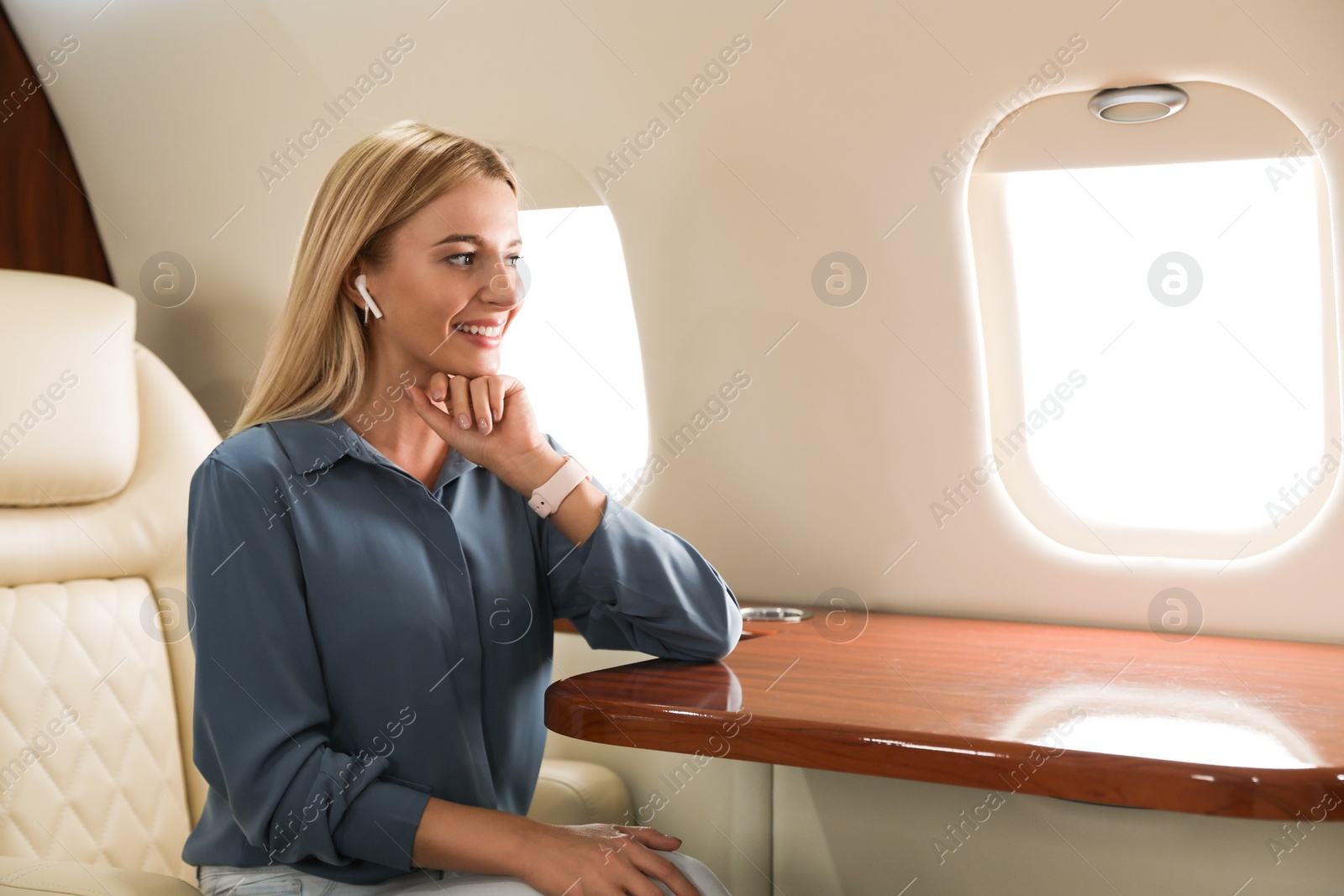 Image of Beautiful woman listening to music via wireless earphones during flight. Air travel