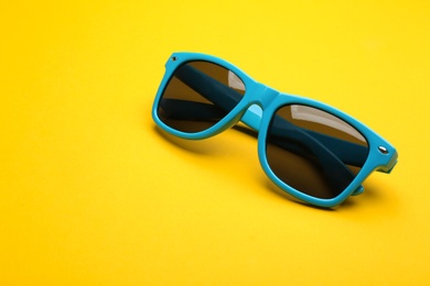 Stylish sunglasses on yellow background, space for text. Fashionable accessory