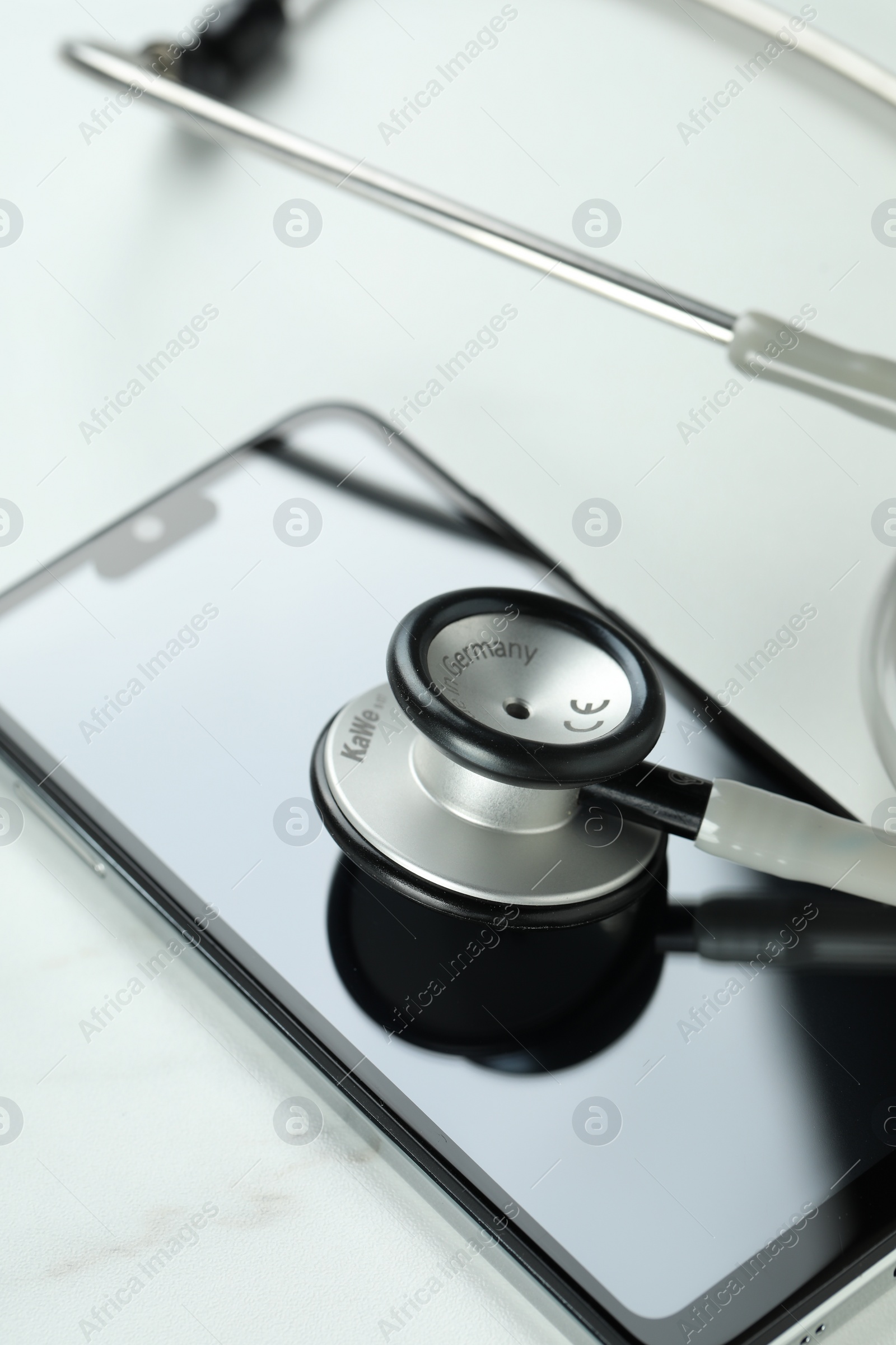 Photo of Modern smartphone and stethoscope on white table, closeup