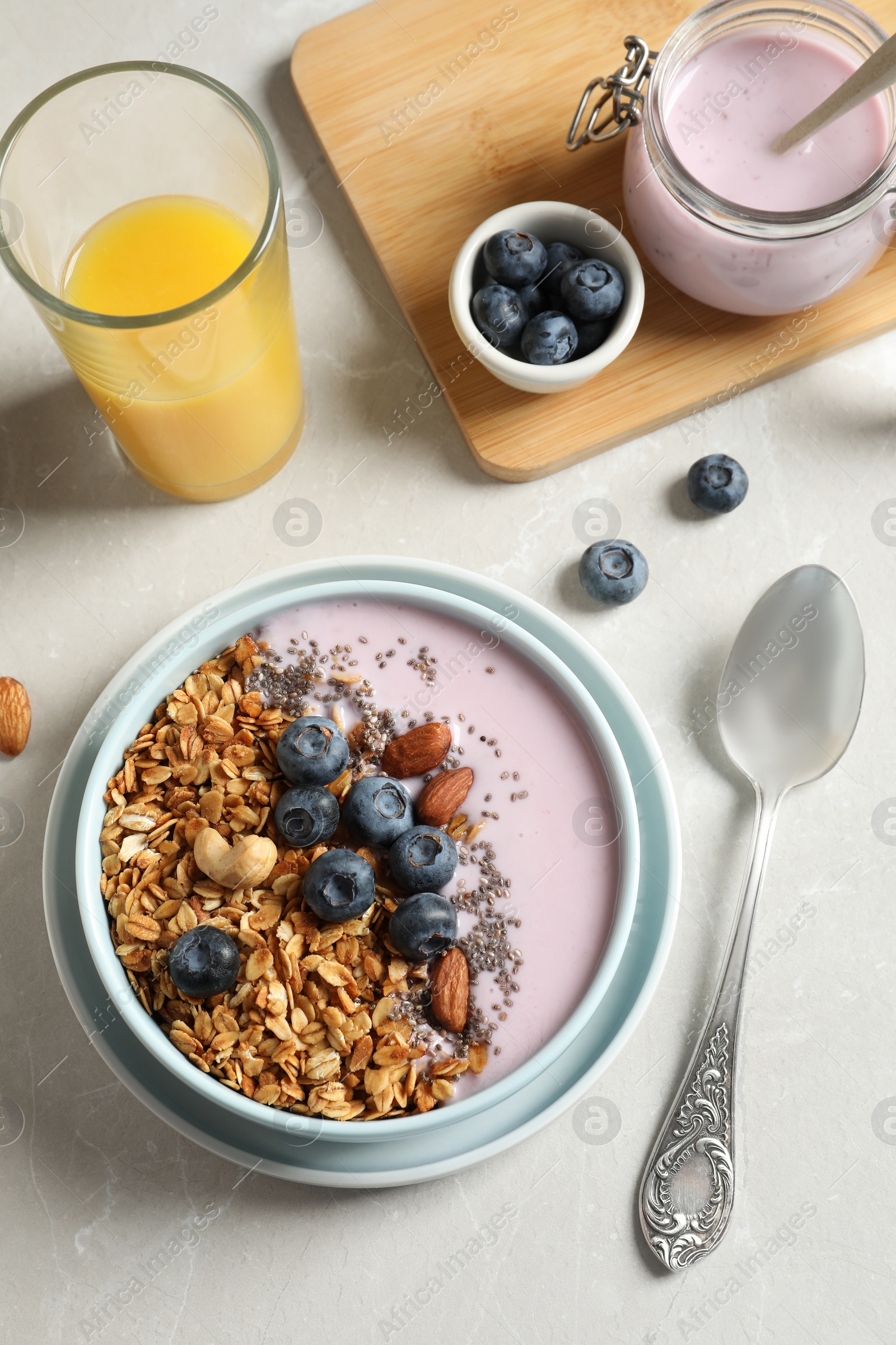 Photo of Bowl of tasty oatmeal with blueberries and yogurt on light grey marble table, flat lay