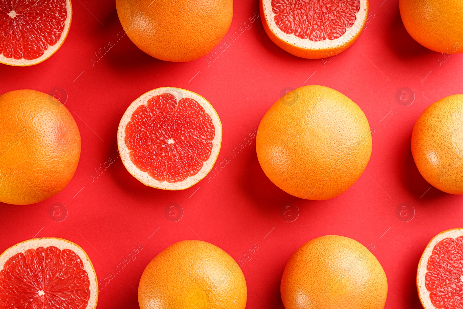 Photo of Cut and whole ripe grapefruits on red background, flat lay