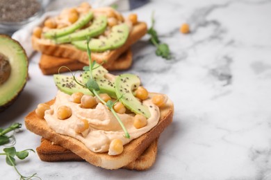 Photo of Delicious sandwiches with hummus, avocado and chickpeas on white marble table. Space for text