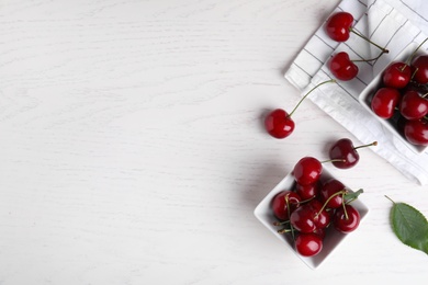 Photo of Flat lay composition with sweet cherries on white wooden table. Space for text