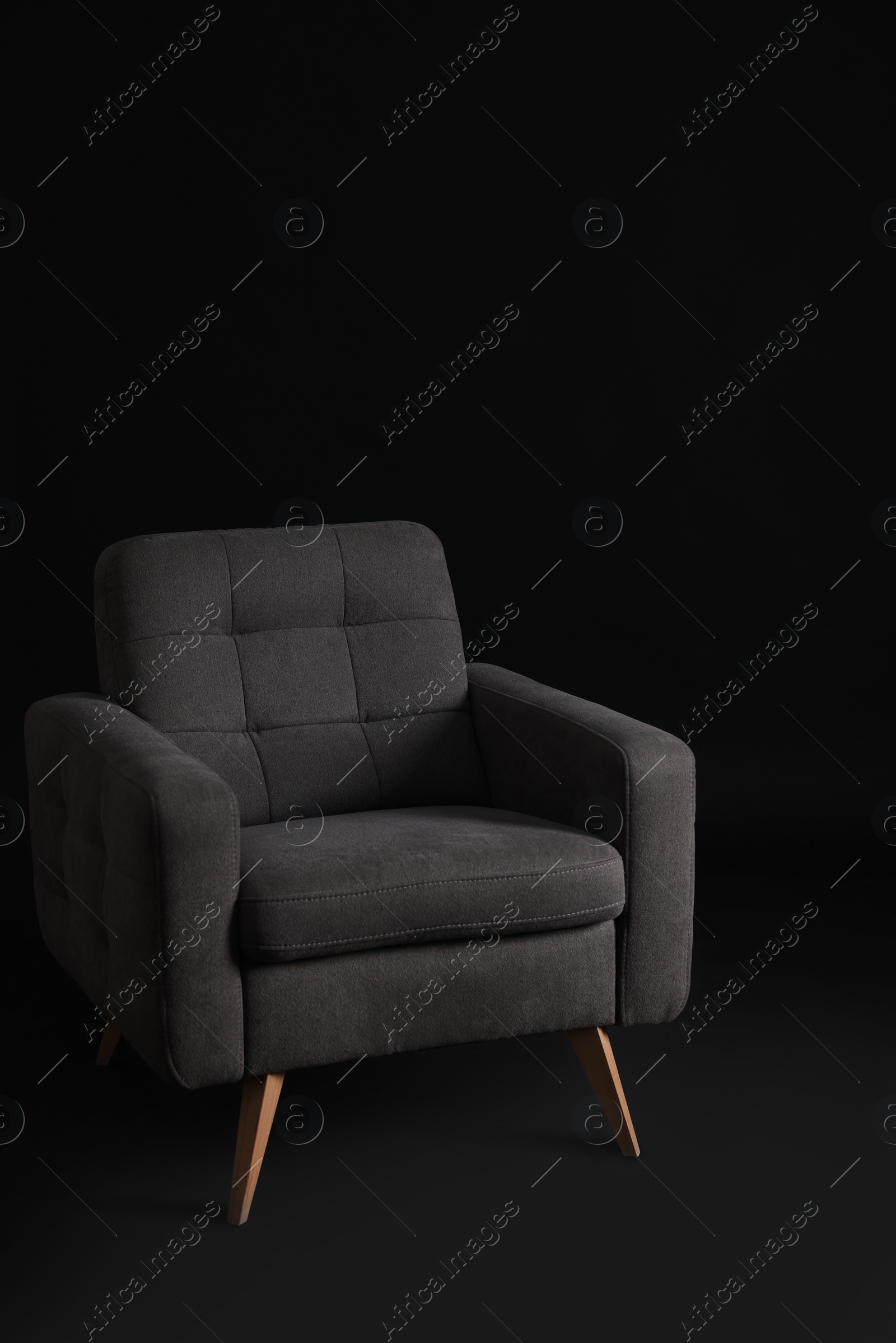 Photo of Stylish comfortable grey armchair on black background