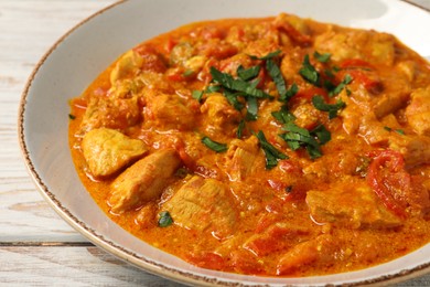 Photo of Delicious chicken curry on wooden table, closeup