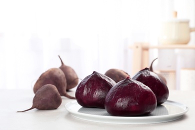 Photo of Plate with ripe peeled beets on table