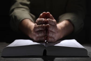 Religion. Christian man praying over Bible at table, closeup