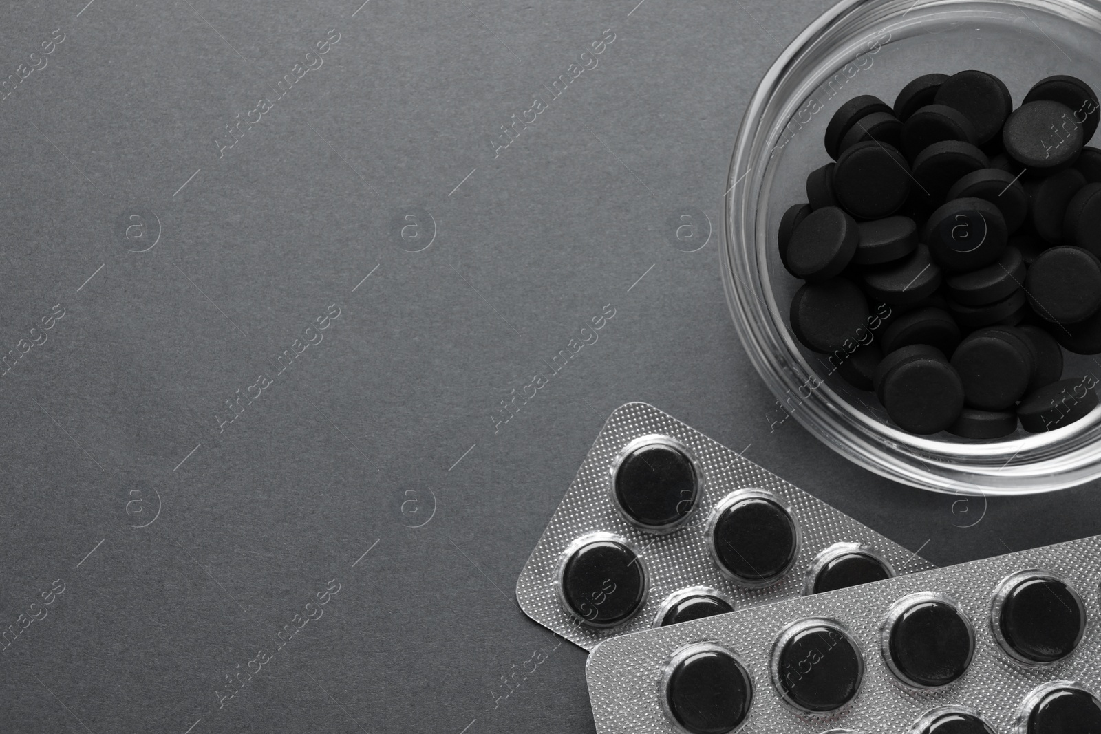 Photo of Activated charcoal pills on grey background, flat lay with space for text. Potent sorbent