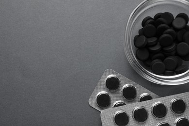 Activated charcoal pills on grey background, flat lay with space for text. Potent sorbent